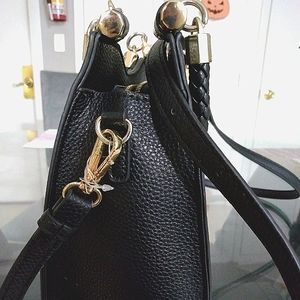 Black leather and faux gold purse with braided handle and stud legs on base.